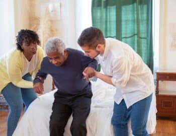 A-Man-and-a-Woman-Assisting-an-Elderly-Man-in-Standing